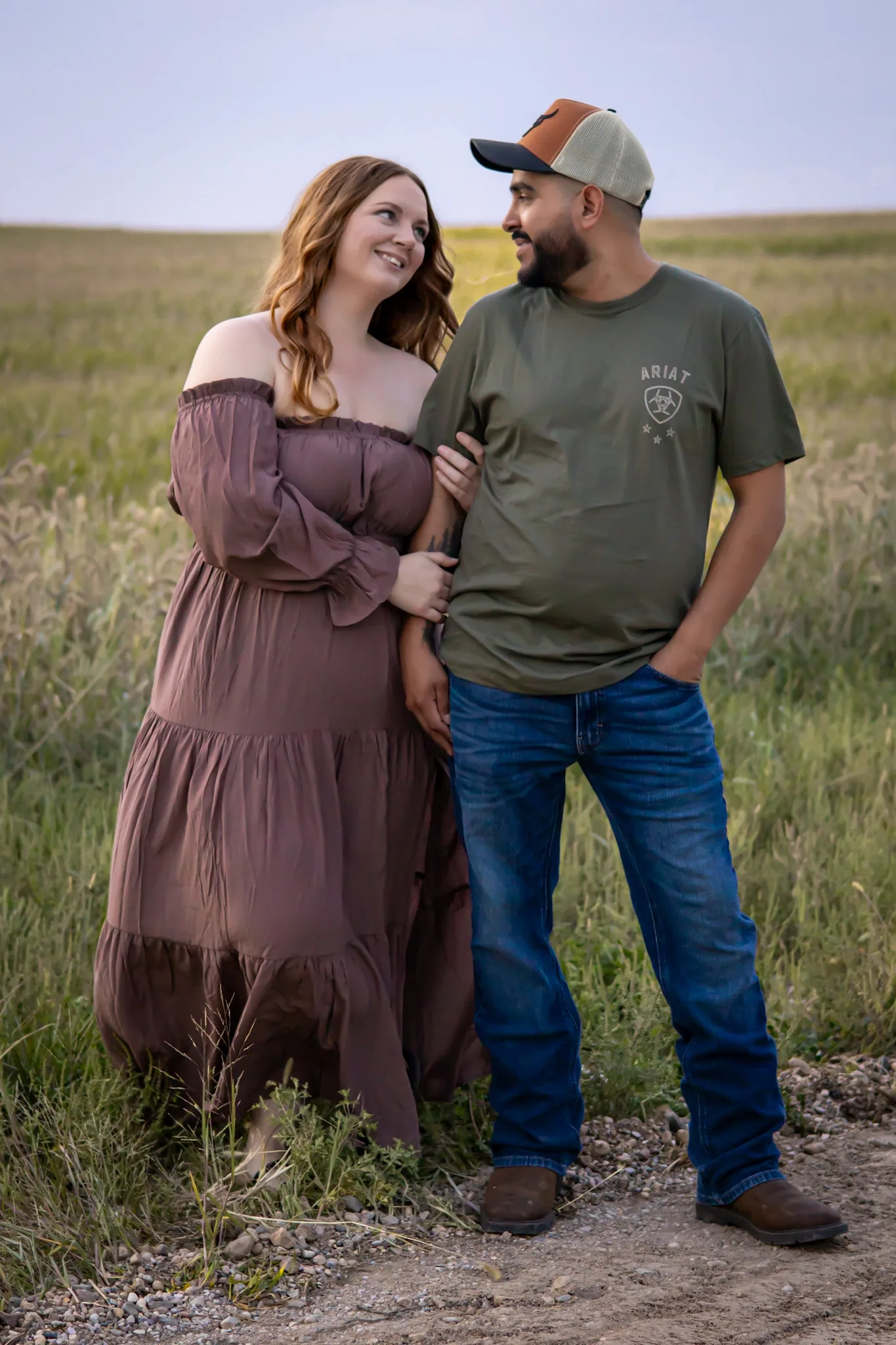 Couple walking hand in hand through an open field.