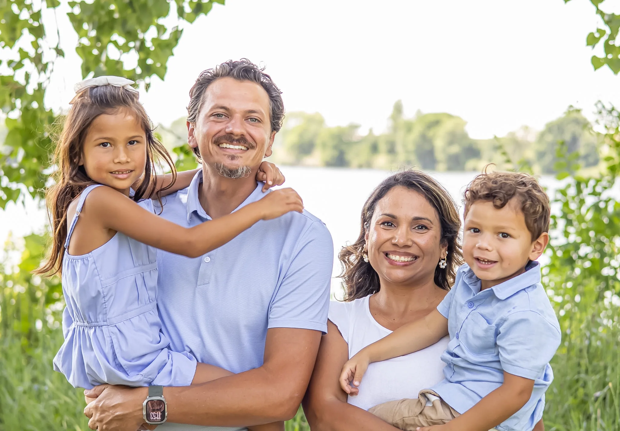 Family of four smiling together outdoors.