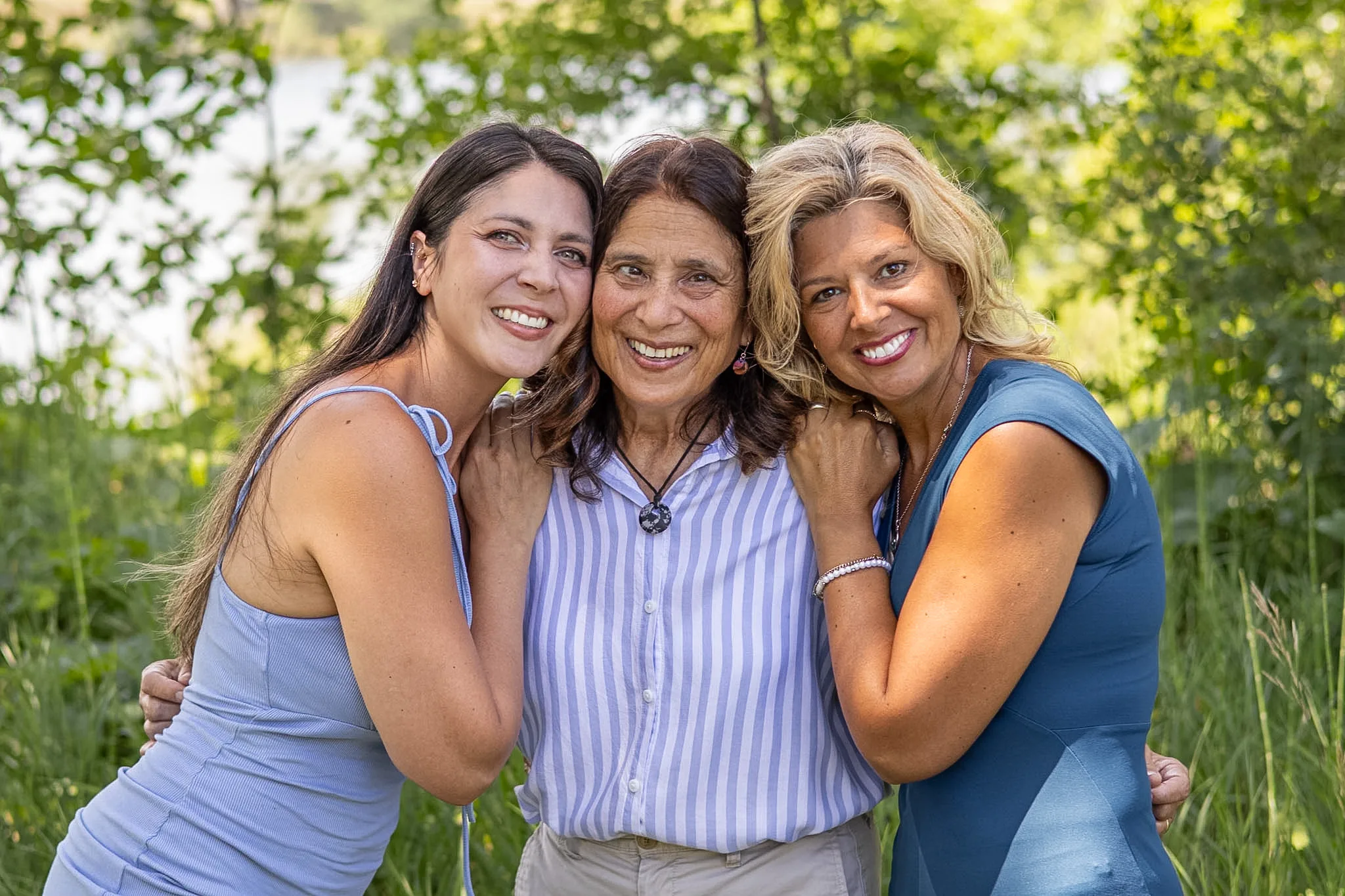 Three generations of women smiling together outdoors.