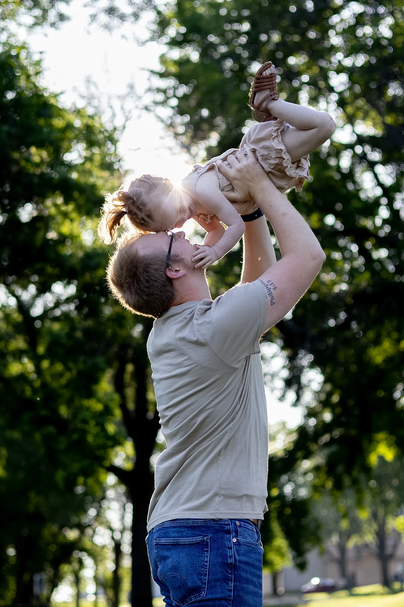 Father lifting his baby into the air outdoors.