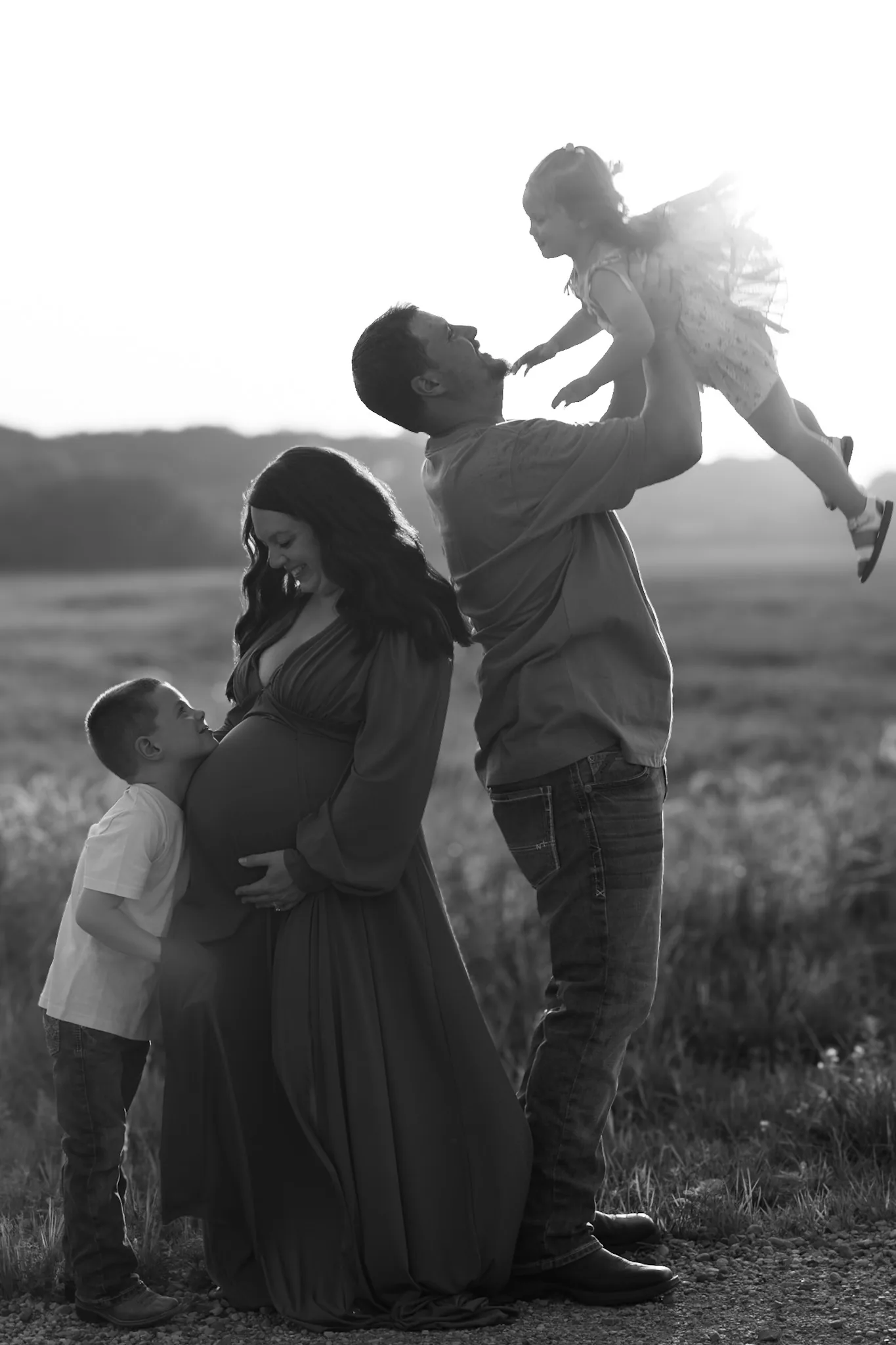 Family gathered around an expectant mother in a black-and-white portrait.