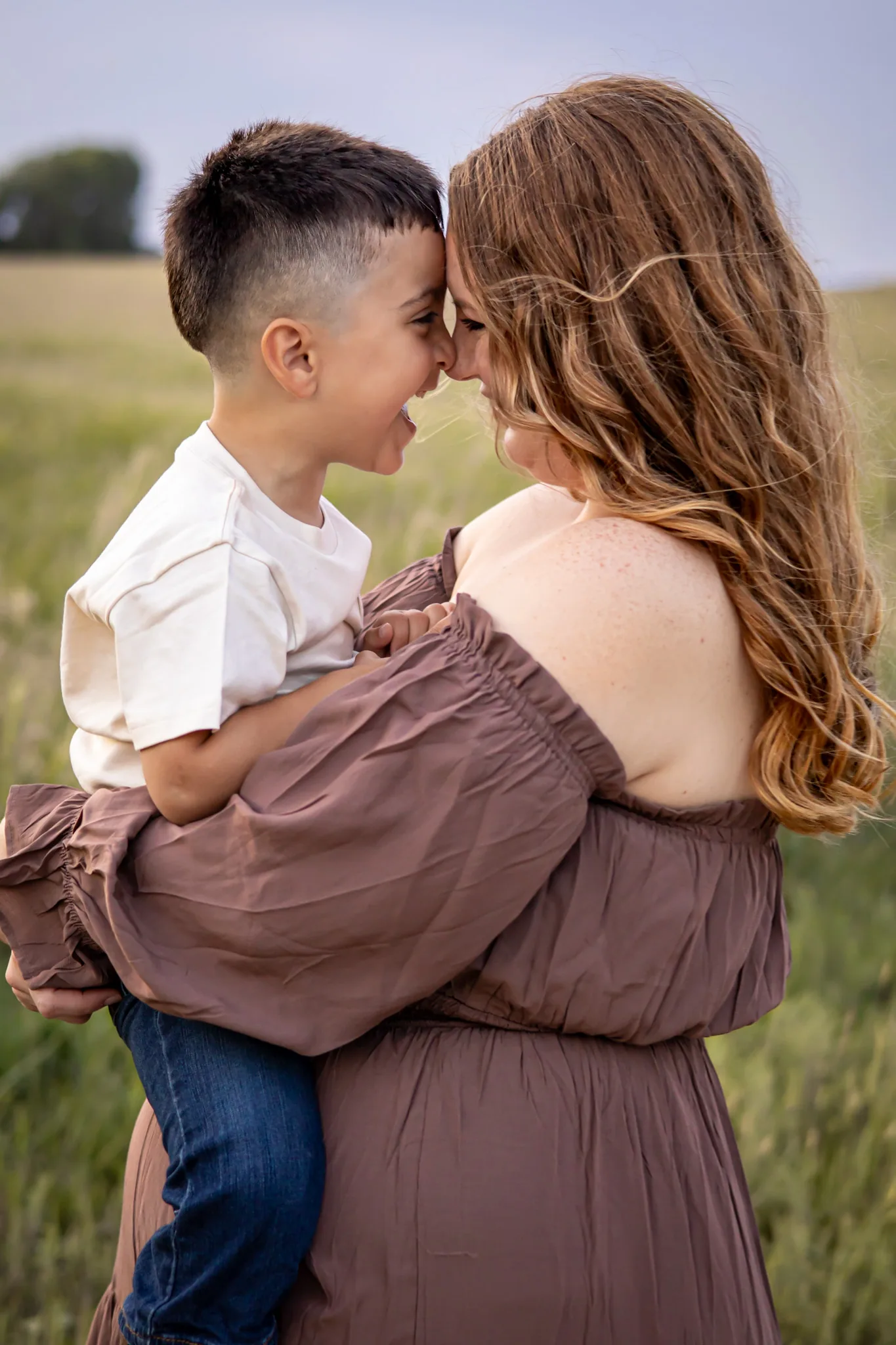 Mother holding her young child close in an open field.