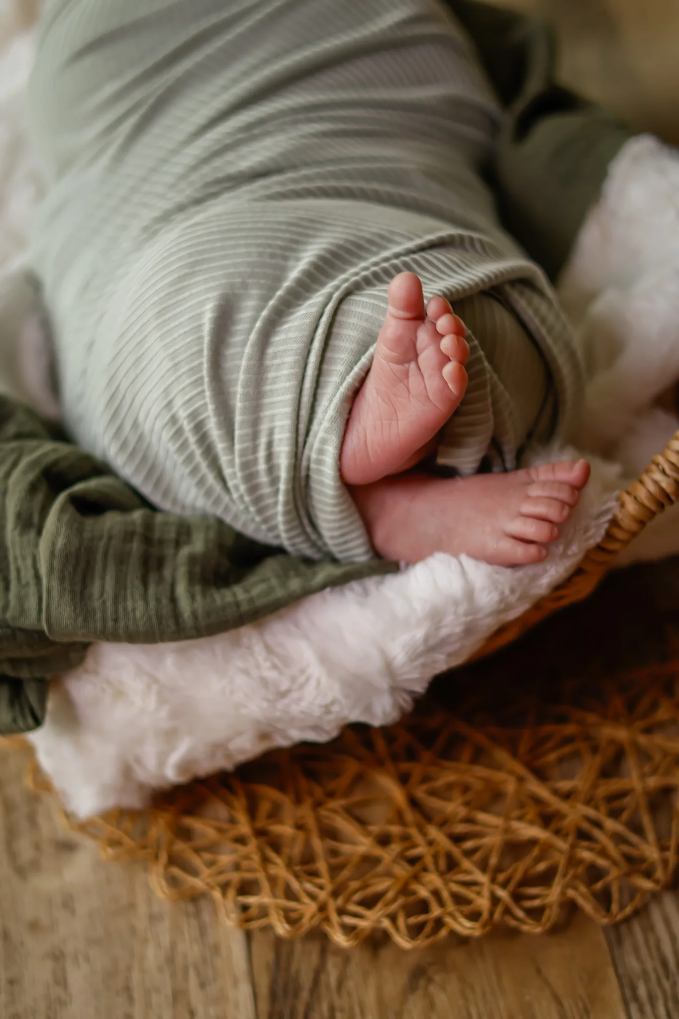 Newborn feet wrapped in a soft green blanket.