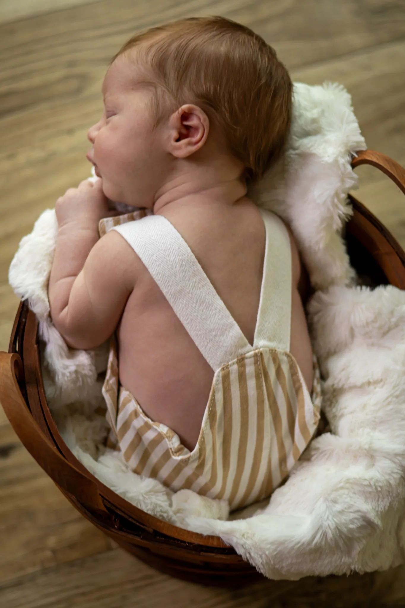 Sleeping newborn resting in a softly lined basket.